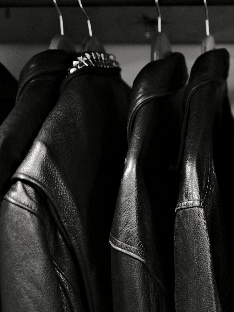 A dense row of black leather jackets on a rail.