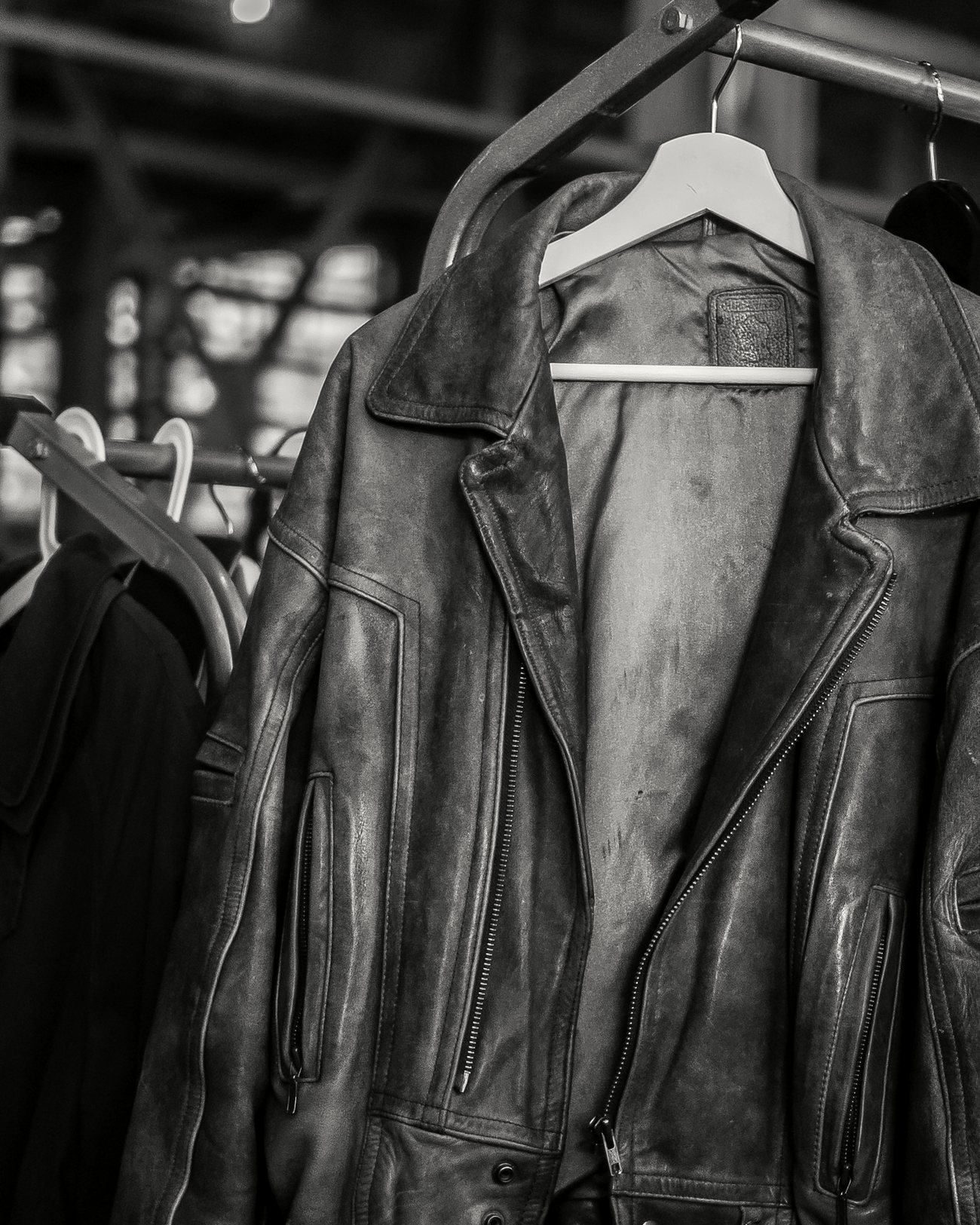 Worn leather jackets on wooden hangers.
