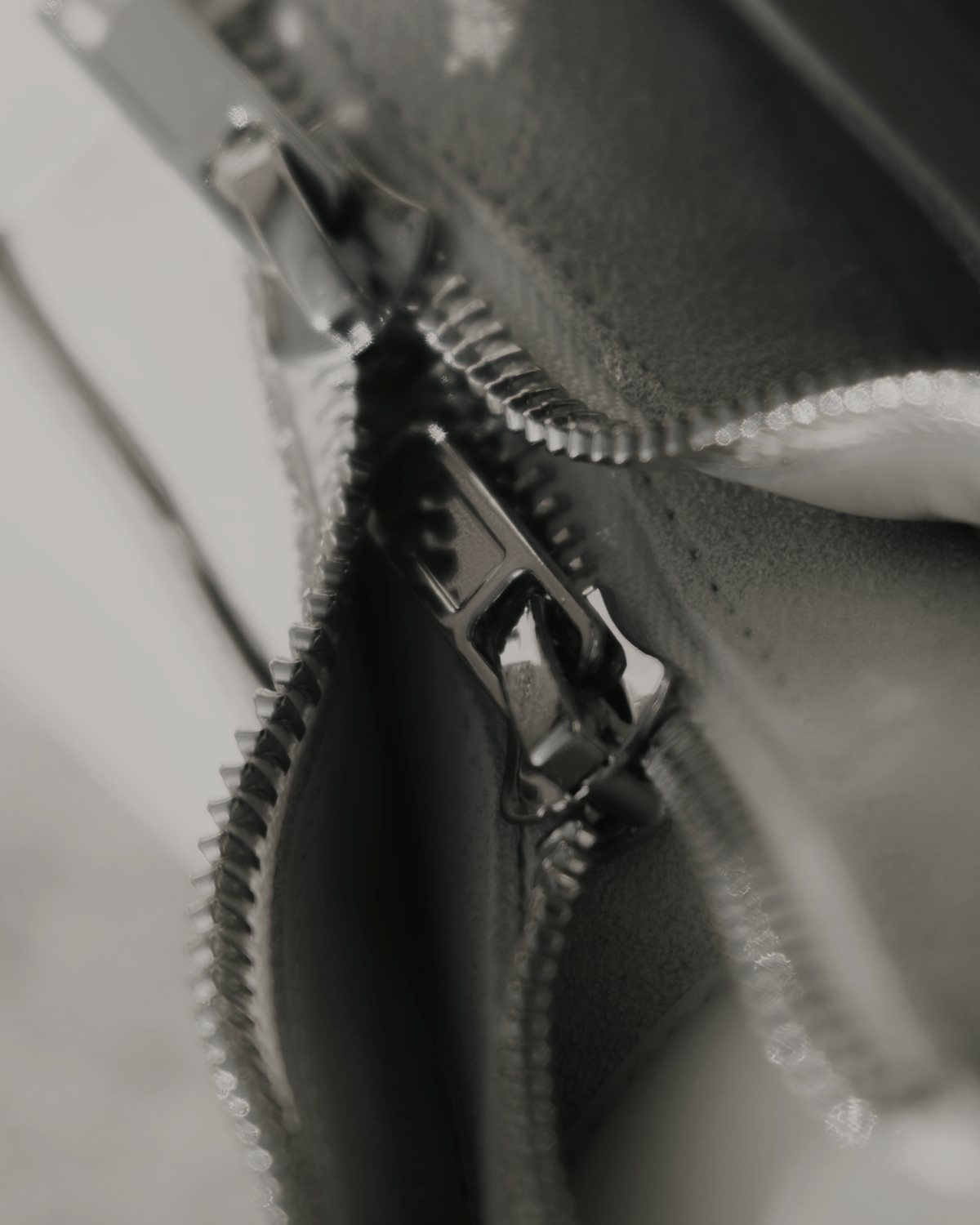 A metal zipper running across grey fabric.