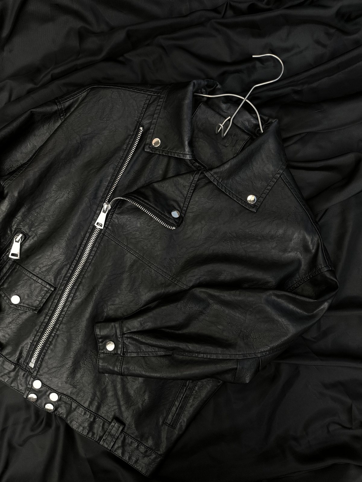 A black leather jacket laid flat in low light.